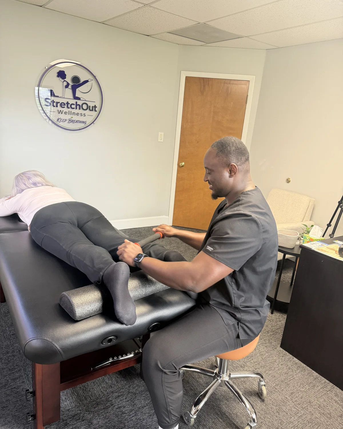 Deen Ali working a client's calf on the table at StretchOut Wellness, Tampa